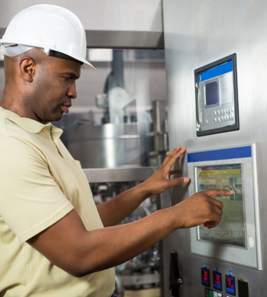 Confident male employee operating machine in manufacturing industry Confident male employee operating machine in manufacturing industry